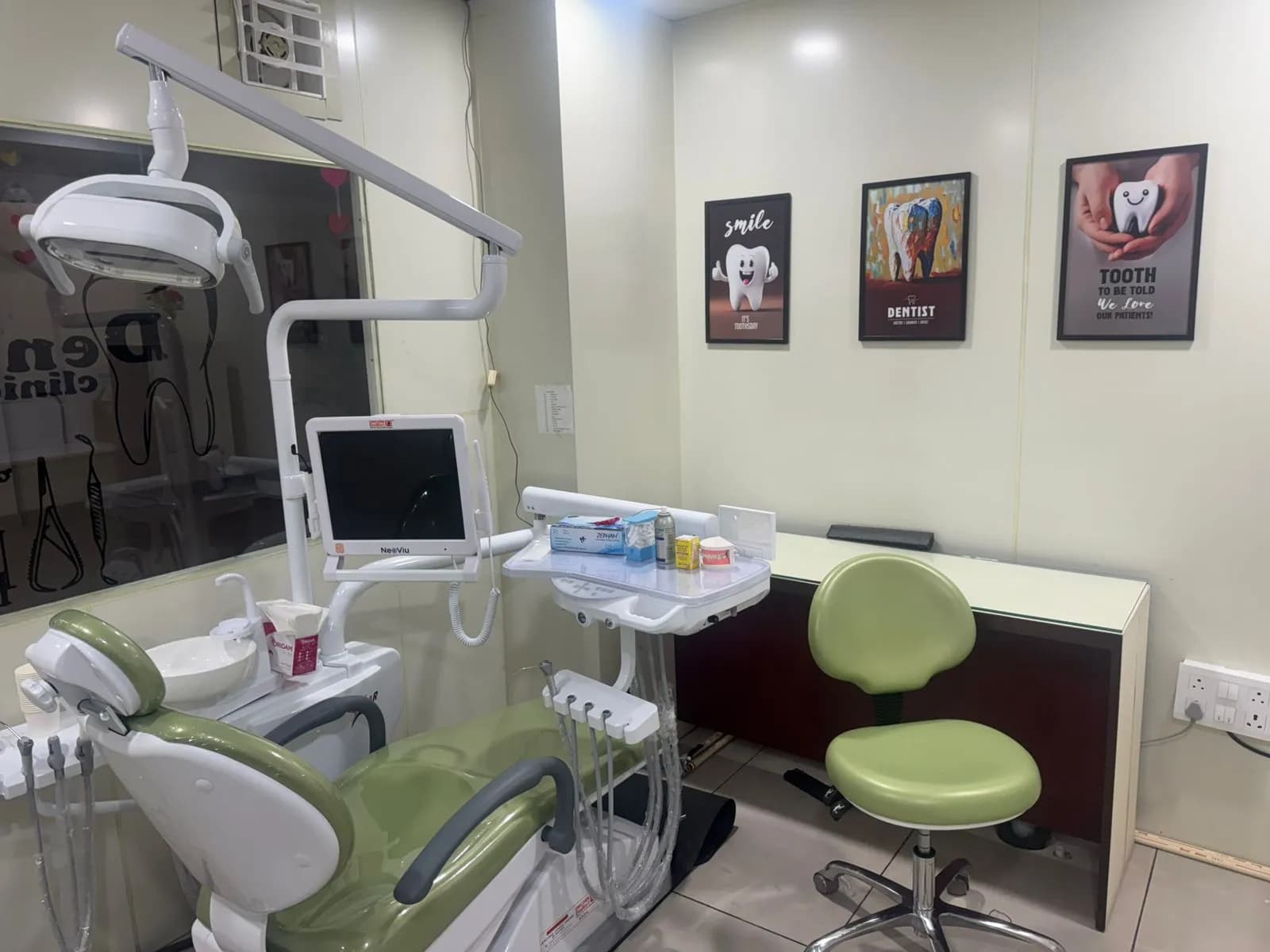 The dental chair under its overhead light, with an intraoral camera screen mounted beside the instrument tray.