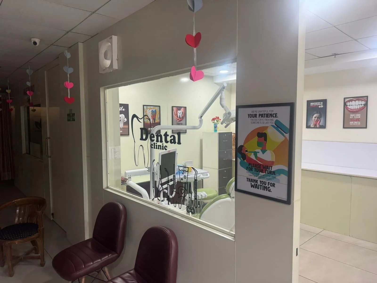 Seating in the corridor outside the treatment room, with an interior window looking through to the dental chair.
