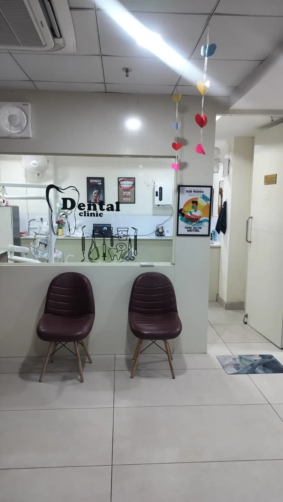 The waiting area, with two chairs beside the reception counter and the clinic's tooth graphic on the glass.